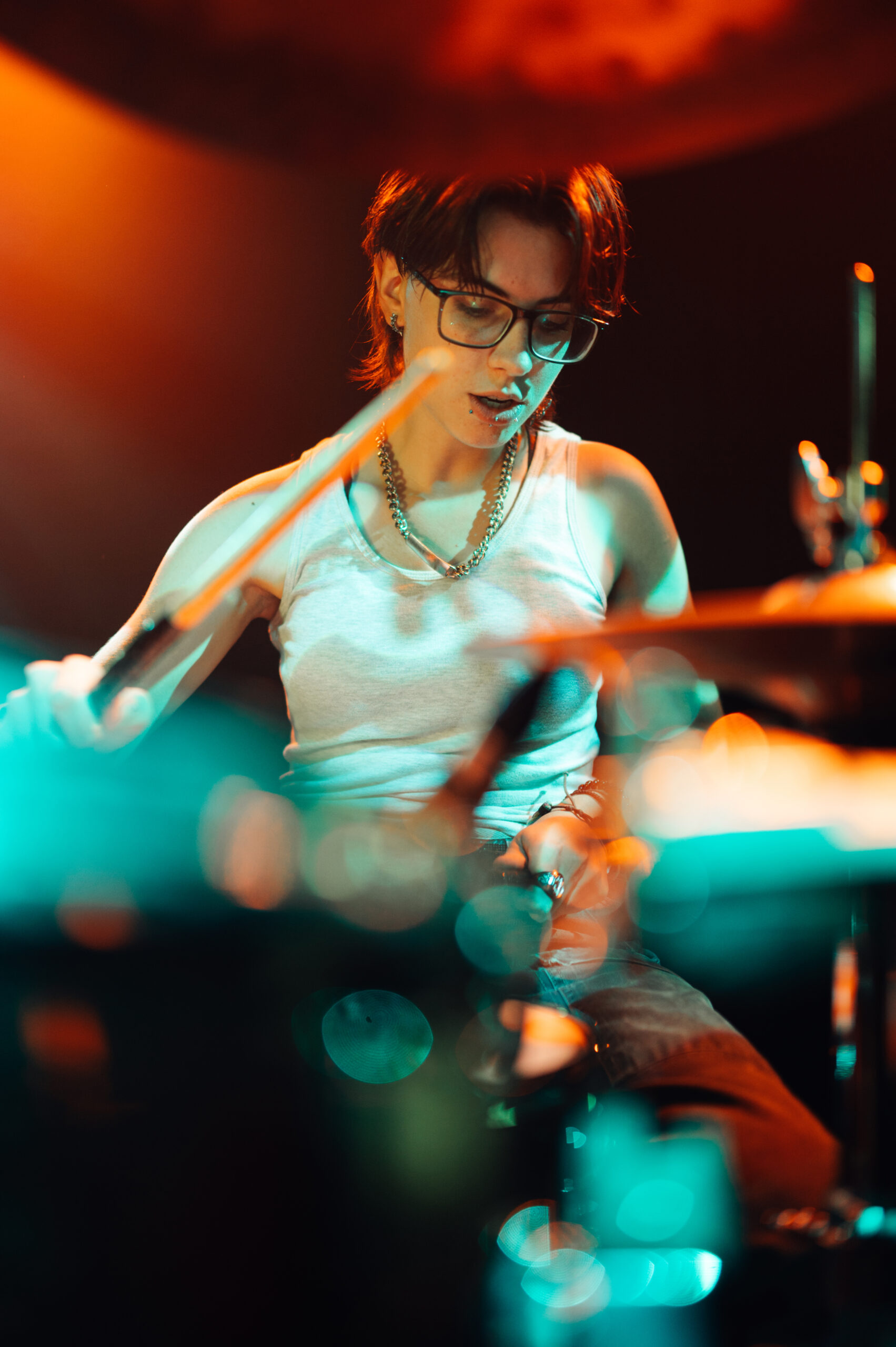 Drummer playing drums on stage with colorful lighting