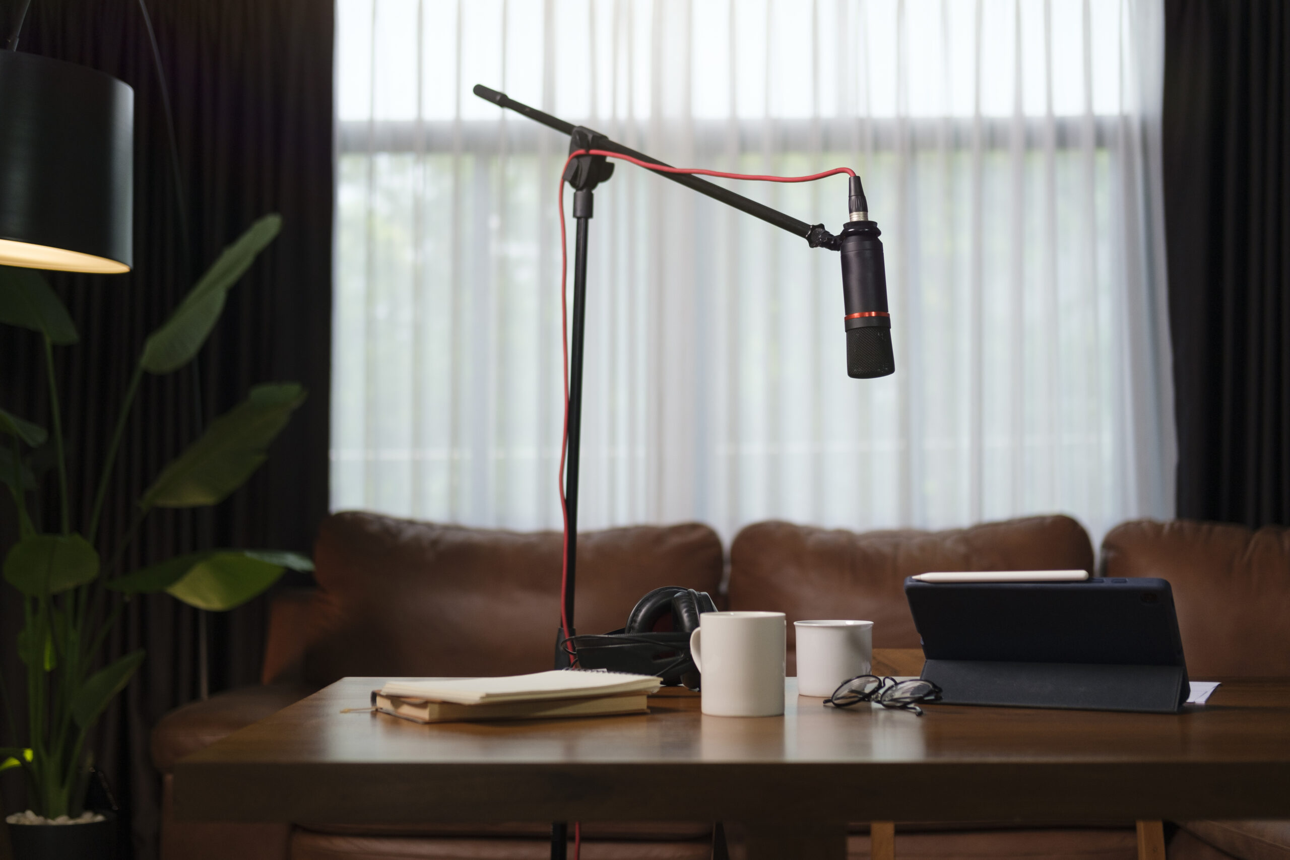 Sound recording and broadcasting equipment with microphone, laptop and headphones on wooden table in the home studio. Podcasting, broadcasting concept.